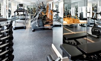 A spacious room with multiple exercise equipment, including an indoor weight machine positioned in the center at Dorsett Mongkok Hong Kong