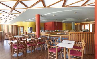 a restaurant with wooden tables and chairs , a red pillar , and a long counter filled with utensils at B&B Hotel Affi - Lago di Garda