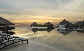 a serene beach scene with a large body of water , a wooden deck , and several lounge chairs placed around it at Avani Sepang Goldcoast Resort