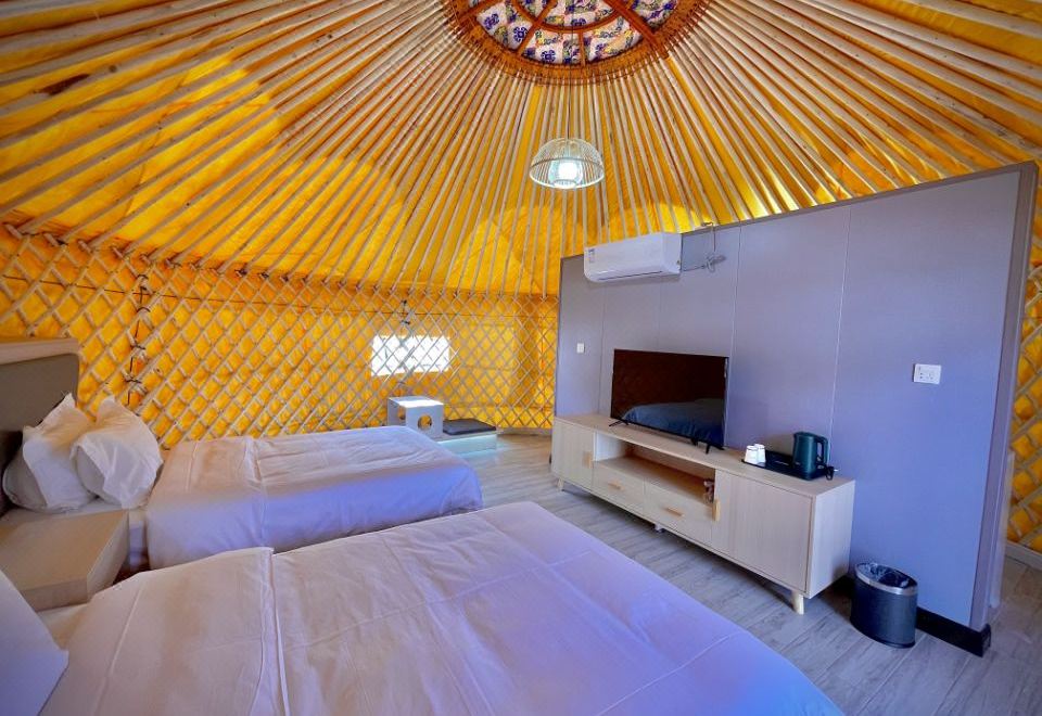 The inside room has white walls and is furnished with a bed and a couch, with yellow decorations on the ceiling at Colorful Danxia Yimi Sunshine Inn