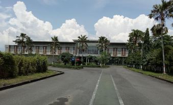 a large , modern building with a long driveway and palm trees in front , under a blue sky dotted with clouds at Hotel Bonero Residence