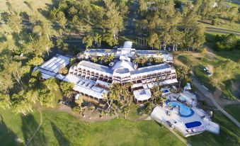 a bird 's eye view of a large hotel with multiple buildings and a pool surrounded by trees at The Kooralbyn Valley