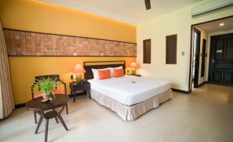 a large bed with white linens and orange pillows is in a room with yellow walls at Pandanus Resort