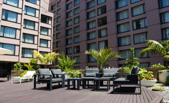 a patio area with several chairs and a table , surrounded by tall buildings in the background at Grand Millennium Auckland