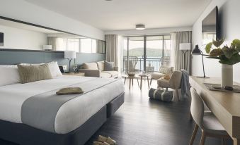 a spacious bedroom with a large bed , a chair , and a balcony overlooking the ocean at Daydream Island Resort