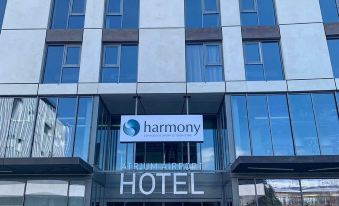 "a large white hotel building with a sign that reads "" harmony hotel "" prominently displayed on the front" at Mercure Geneva Airport