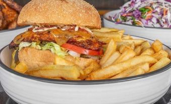 a white bowl filled with a burger and fries is placed on a dining table next to other food items at Quest Cheltenham