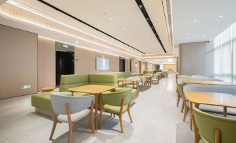 The restaurant features a central area with tables and chairs, as well as an open concept space that incorporates a bar and lounge, creating a welcoming and cozy environment for guests to dine and relax at All Seasons Hotel (Guangzhou Tianhe Sports Center Branch)