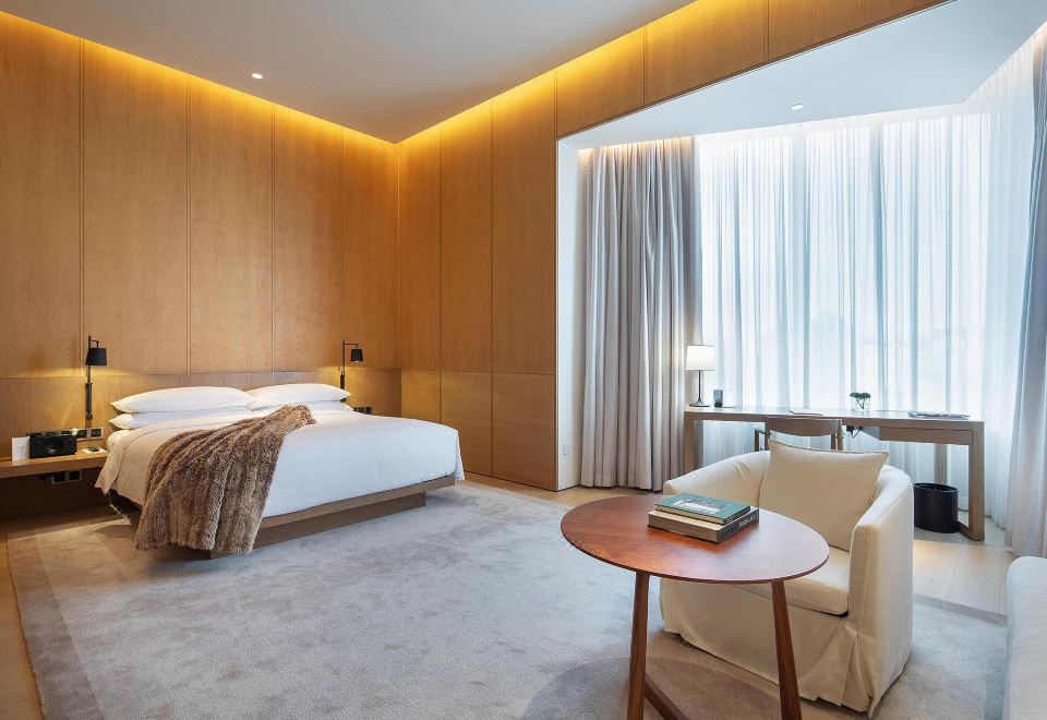a spacious and contemporary bedroom featuring large windows and walls adorned with wooden panels, with the bed positioned alongside them at Green Nest Hotel (Guangzhou Yongtai Metro Station)