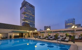 There is a swimming pool in front of a building and cityscape, visible at dusk or night at Holiday Inn Golden Mile