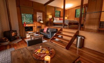 a cozy living room with hardwood floors , a wooden staircase , and a dining area with a table and chairs at Whispering Valley Cottage Retreat