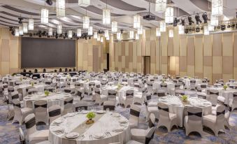 a large banquet hall with multiple round tables covered in white tablecloths and set for a formal event at Melia Vinpearl Hue
