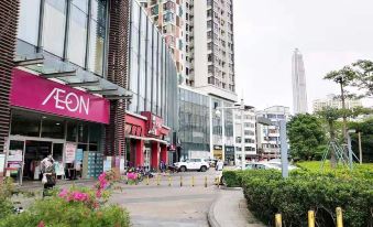 On a city street, buildings and people line the sidewalk next to an empty road at Hejing Hotel (Futian Exhibition Center, Shenzhen)