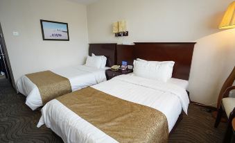 a hotel room with two beds , a nightstand between them , and a framed picture on the wall at Frontier Building