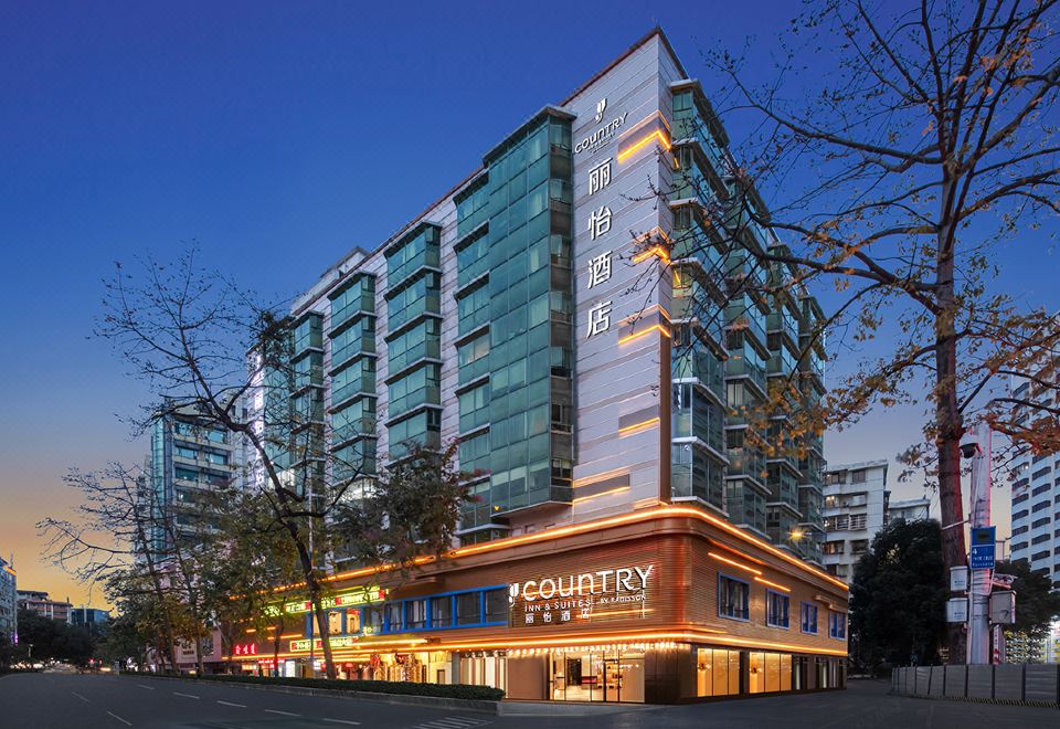 At night, there is a hotel in the foreground with an illuminated building in the background at Country Inn