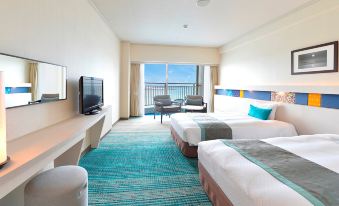 a hotel room with two beds , a television , and a balcony view of the ocean at Loisir Hotel Naha