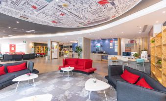 In the middle of the lobby, there are couches, tables, and an area rug at Ibis Hotel (Shanghai New International Expo Center Lianyang Branch)