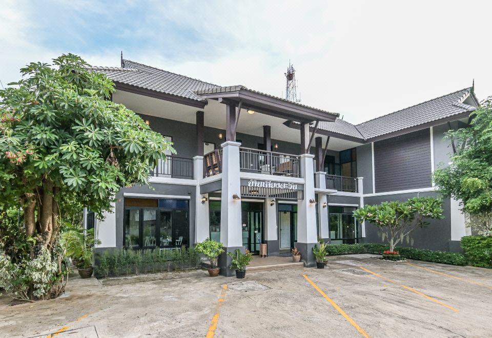 a large house with a balcony and potted plants in front of it , under a cloudy sky at Baan Kieng Tawan