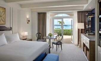 a luxurious hotel room with a king - sized bed , a dining table , chairs , and a balcony overlooking the ocean at Rosewood Bermuda