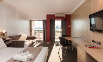 a hotel room with a bed , desk , and sliding glass door leading to a balcony at Metro Hotel Perth
