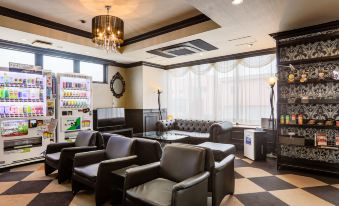 a large , well - lit room with black leather couches and chairs arranged around a dining table at Hotel Wing International Miyakonojo