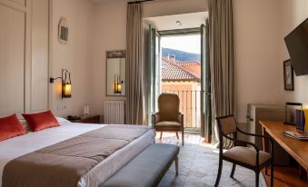 a bedroom with a bed , chairs , and a sliding glass door leading to a balcony at Parador de La Granja