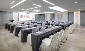 a large room arranged with long tables and chairs facing the front for an event at Peony Hotel(Mudanyuan Subway Station)