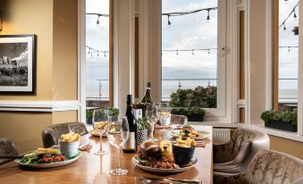 a dining table is set with plates of food , wine glasses , and a bottle of wine at The Beaches Hotel