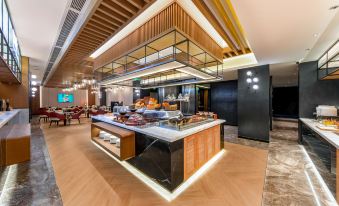 There is an open concept restaurant with tables and chairs located next to the counter in the front at Park Inn by Radisson Guangzhou Railway Station Yuexiu International Congress Center
