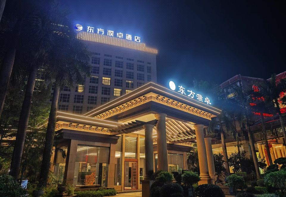 The illuminated entrance of a hotel at night, showcasing its lights, and the view from outside across the street at Fuzhou Oriental Yanzhuo Hotel