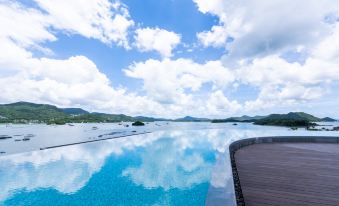 The hotel boasts a stunning large pool with blue water and an island in the middle, offering breathtaking views of mountains and the ocean at WM HOTEL HONG KONG, Vignette Collection