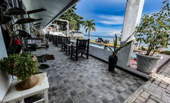 a paved outdoor seating area with a view of the ocean , featuring several chairs and potted plants at The Beachhouse