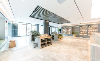 a modern office lobby with a large glass window , multiple potted plants , and a reception desk at Ji Hotel