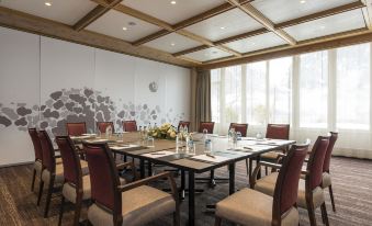 a conference room with a large table surrounded by chairs and a window with white curtains at Sunstar Hotel & Spa Grindelwald