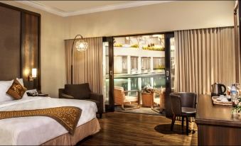 a hotel room with a king - sized bed and a large window overlooking a balcony , providing a view of the city at The Singhasari Resort Batu