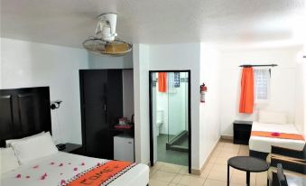 a modern hotel room with a bed , couch , and kitchenette , decorated with red curtains and black flooring at Suva Motor Inn