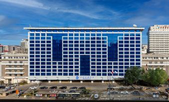 A large building with cars parked in front and an office block on the other side at Beijing Xinqiao Hotel