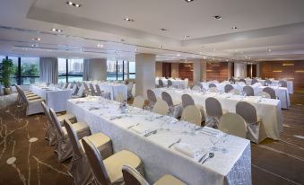a ballroom with tables and chairs arranged for an event at The Harbourview-Chinese YMCA of Hong Kong
