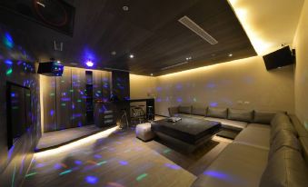 a modern living room with a large couch and several chairs , illuminated by colorful lights at Platinum Hotel