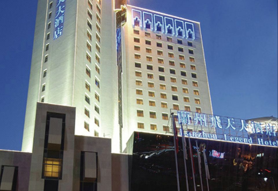 a tall , modern building with blue lights illuminating the structure , creating a festive atmosphere at night at Lanzhou Feitian Hotel (Lanzhou University Subway Station)