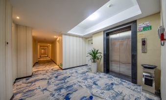 There is a spacious hallway with carpeted flooring and an elevator located in a separate room at one end at Fortune Hotel