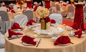 a large , round table with white tablecloths and red napkins is set up in a ballroom for an event at Travelodge Ipoh