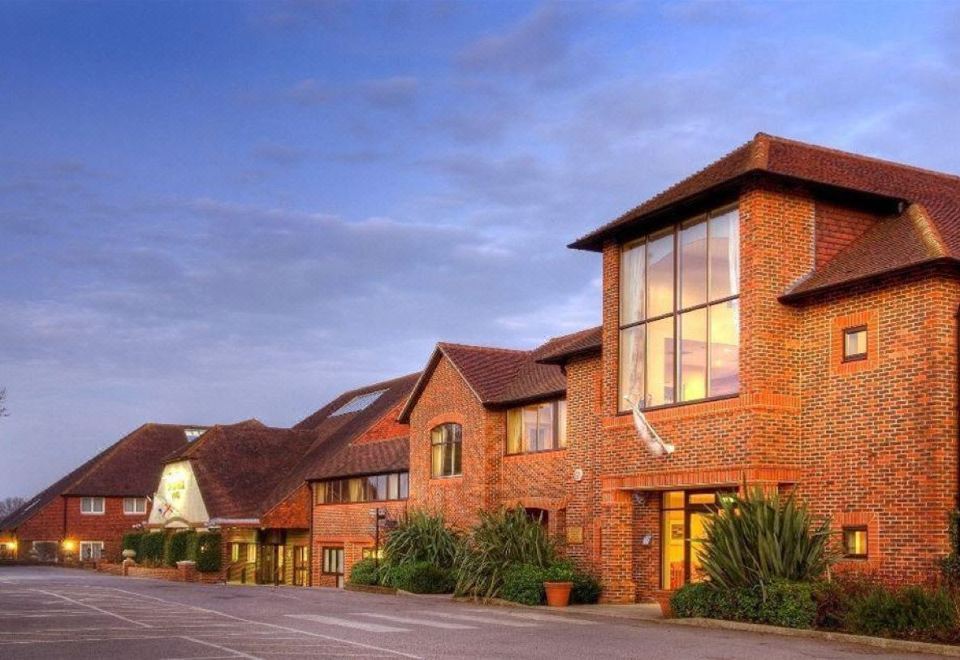 a brick building with large windows is situated on a street , surrounded by trees and bushes at Dale Hill Hotel