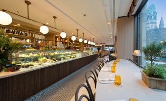 a dining area with a long table and chairs , as well as a buffet table with various food items at Waldorf Astoria Berlin