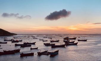 A group of people is standing on the ocean at sunset, with boats in front and one large body of water at Shengsi wolfberry island on the island to the fisherman's family