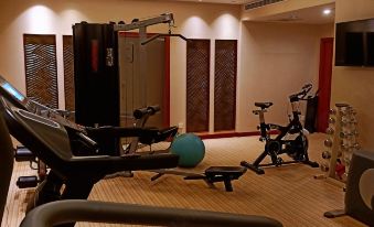 A gym is shown with multiple exercise equipment, including an indoor weight machine in the center at Shanghai Shaanxi Business Hotel