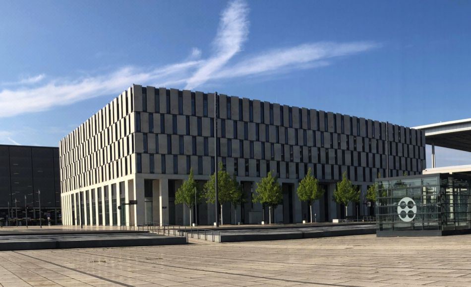 a modern , gray building with a black and white pattern is surrounded by trees and modern buildings at Steigenberger Airport Hotel Berlin