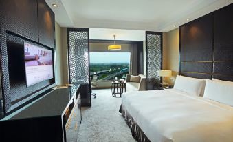 a modern hotel room with a large bed , desk , and sliding glass door leading to a balcony overlooking a cityscape at Crowne Plaza New Delhi Mayur Vihar Noida