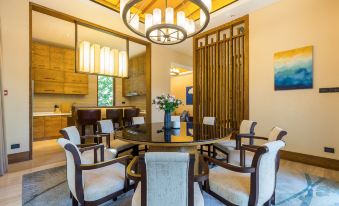 a large dining room with a round table surrounded by white chairs , and a chandelier hanging above at Sanya Haitang Bay Island Villa (International Duty Free City Branch)