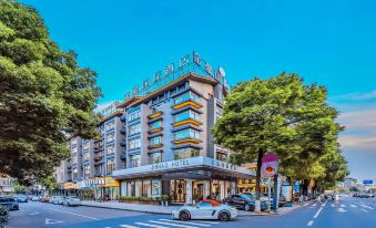 There is an office building in the city with cars parked on the street, and there is a hotel located across from it at Jinhao International Hotel